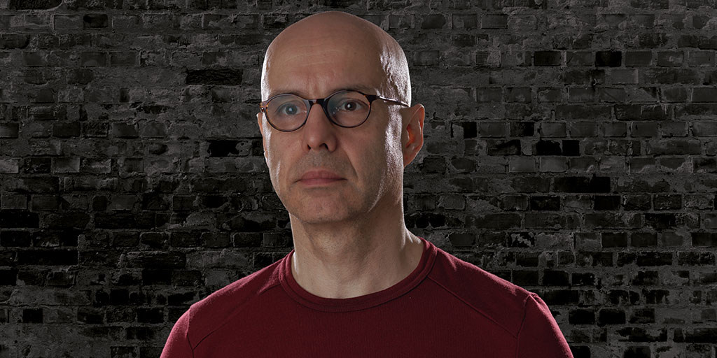 Porträt von Peter Waesch vor einer Ziegelmauer